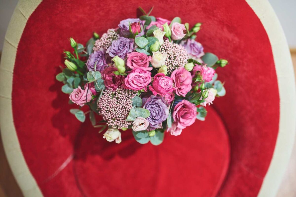 A beautiful premium bouquet tied with silk ribbons lace placed on a red velvet backdrop.