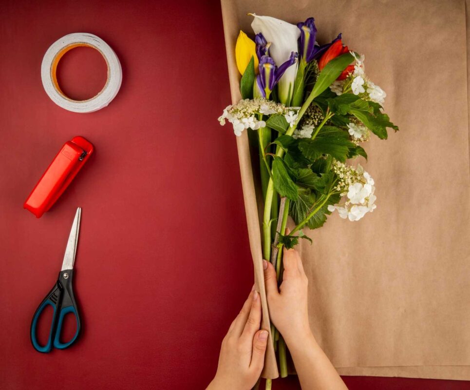 Top view of a female hands wrapping prefectly cut flowers.