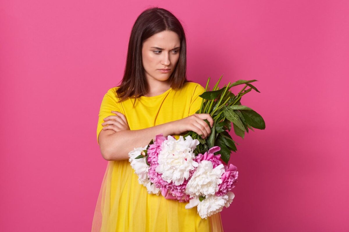 Calgary Florist | What to Do If Your Delivered Flower Bouquet Don't Meet Expectations? A young woman holding a bunch of flowers and looks disappointed with the flowers delivery.